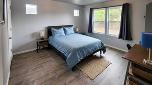 Een slaapkamer met een bed, nachtkastjes, een raam met gordijnen en uitzicht op de omgeving.