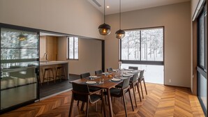 Ett modernt matområde med ett stort träbord som är dukat för sex personer, omgivet av stolar.