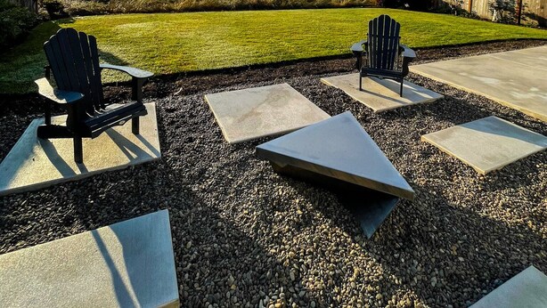 A patio with Adirondack chairs and a view of a grassy field.