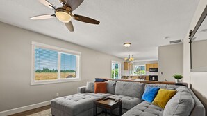 A modern living room with a sectional sofa, a small coffee table, and a ceiling fan.