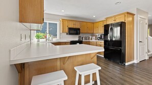 A modern kitchen with wooden cabinets, a black refrigerator, and a white countertop.