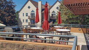 A patio area with outdoor seating, a grill, and red umbrellas.