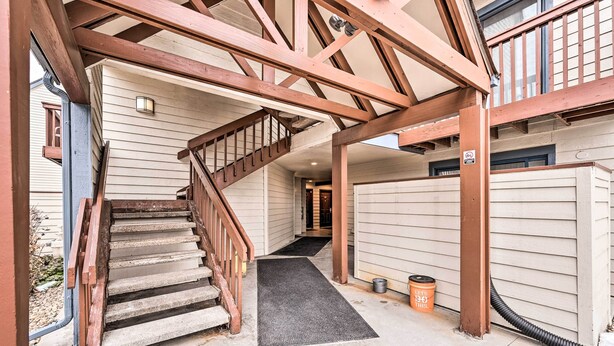 A staircase with wooden railings leading to a covered area with a view of a building.