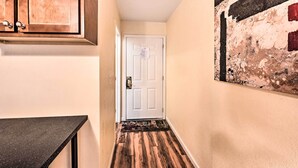 A hallway with a wooden floor, a white door, and a painting on the wall.