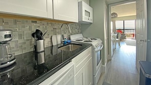 A modern kitchen with white cabinets, a black countertop, a stove, and a microwave. - Ocean Dunes by Palmetto Vacations (Myrtle Beach)
