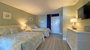 A hotel room with two beds, a dresser, a television, and a door with a sign. - Ocean Dunes by Palmetto Vacations (Myrtle Beach)