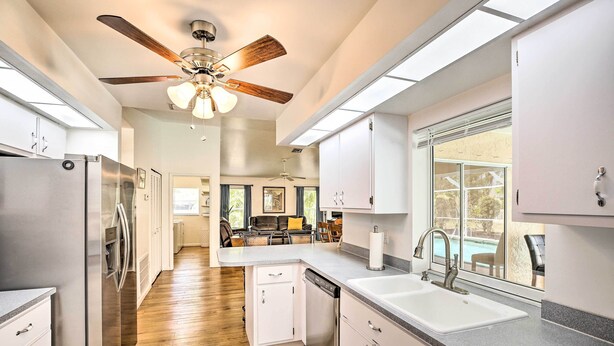 A modern kitchen with a built-in dishwasher, stainless steel appliances, and a large window offering a view of the outdoors. - Breezy Cape Coral Oasis, Covered Lanai & BBQ (Cape Coral)