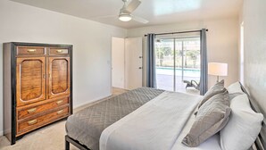 A bedroom with a bed, a wardrobe, a ceiling fan, and a view of the outside. - Breezy Cape Coral Oasis, Covered Lanai & BBQ (Cape Coral)