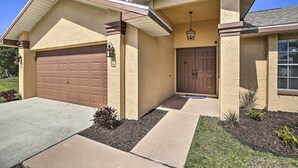 A residential house with a garage, a front door, and a small porch area. - Breezy Cape Coral Oasis, Covered Lanai & BBQ (Cape Coral)