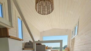 A compact, modern room with a loft bed, built-in storage, and a view of the outdoors. - Under Canvas Bornholm (Østermarie)