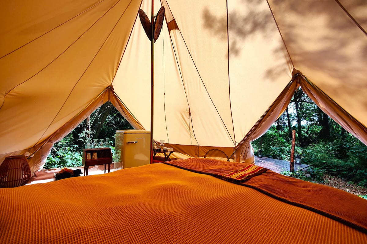 Una carpa con una cama, una mesita y un refrigerador.