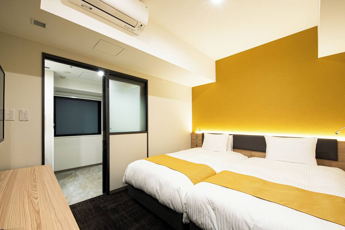 Une chambre d’hôtel comprenant un lit, des tables de chevet, un bureau, un miroir et une armoire.