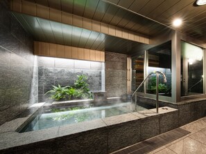 Een moderne spa met een whirlpool, een douche in glazen wanden en een verticale tuin.