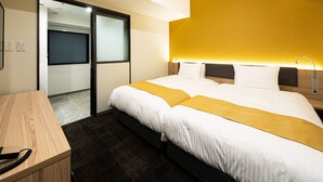 Habitación de hotel con cama, escritorio y puerta corredera que da a un baño.