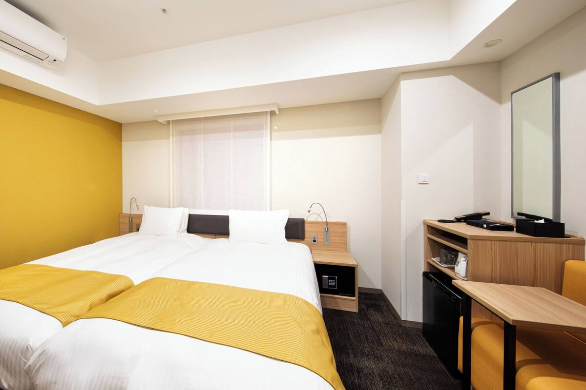 Une chambre d’hôtel comprenant un lit, une table de chevet, un bureau, une chaise et un grand miroir.