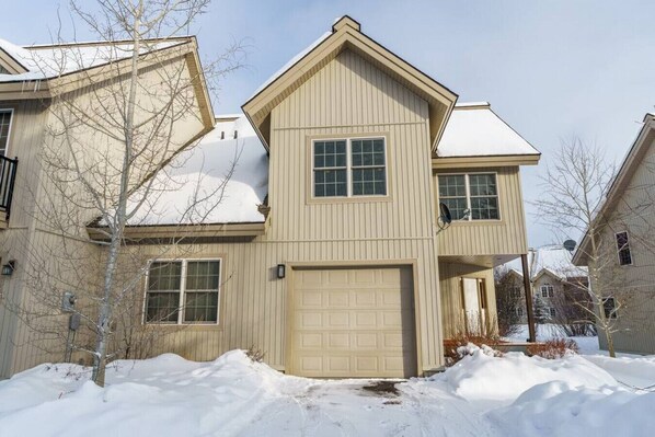A two-story house with a garage, a large window, and a satellite dish.