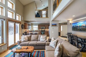 A spacious living room with a large sectional sofa, a coffee table, and a dining area with a table and chairs.