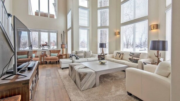 A spacious living room with a large window, a fireplace, and a cozy seating area. - Aspen Pointe Glass House on Ski Hill Road Driggs, ID (Driggs)