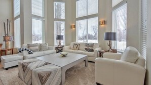 A spacious living room with large windows, a sectional sofa, a coffee table, and two side chairs. - Aspen Pointe Glass House on Ski Hill Road Driggs, ID (Driggs)