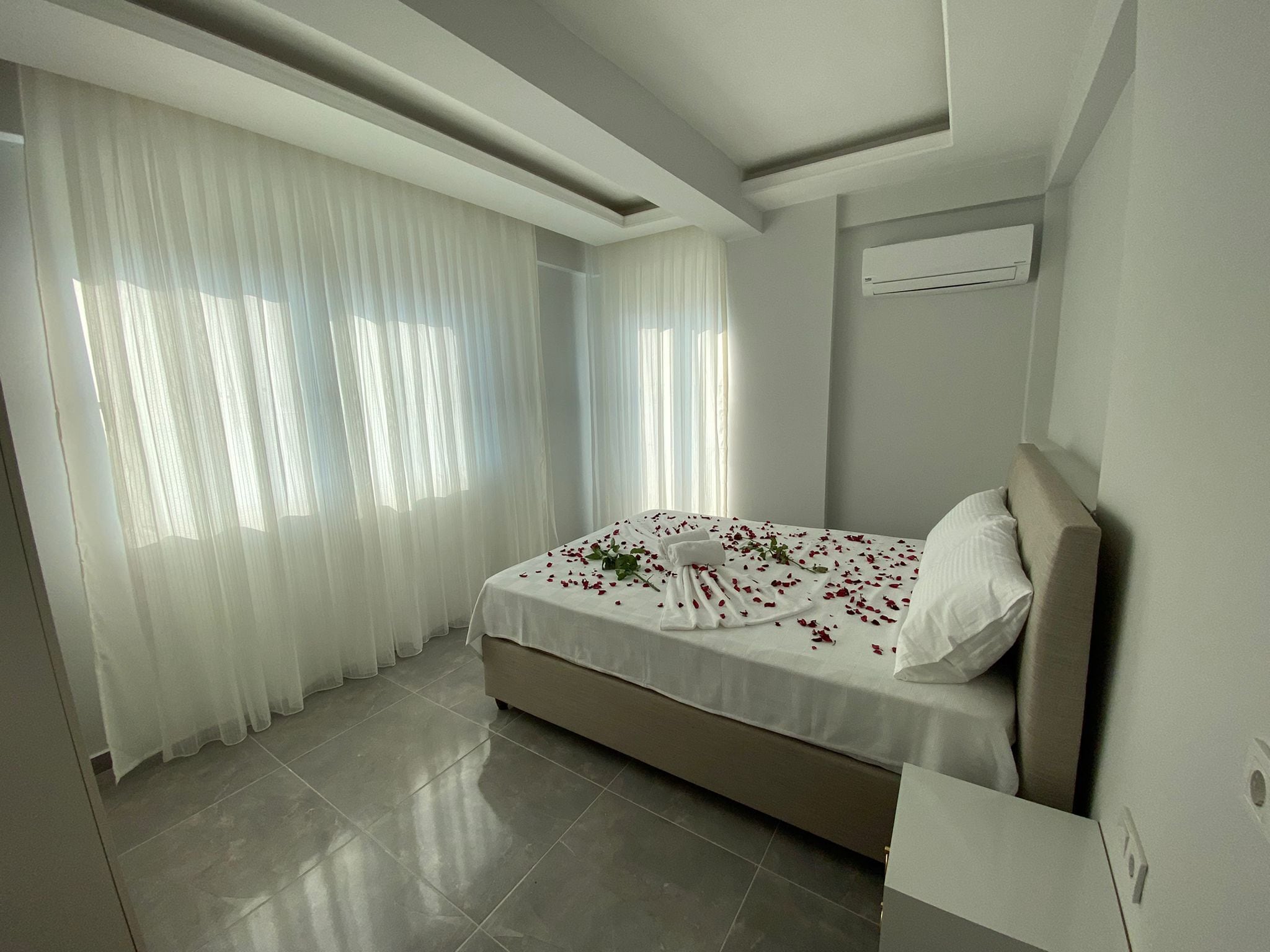 Un dormitorio moderno con cama, cortinas y aire acondicionado.