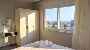 A hotel room with a bed, a wardrobe, a mirror, and a window with a city view. - Soral Apart Otel (Demre)