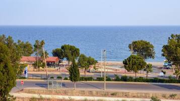 Una carretera costanera amb una vista despejada del mar, una àrea de pàrquing i un edifici amb teulada vermella.