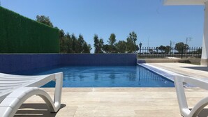 A swimming pool with a tiled edge and a green hedge. - Soral Apart Otel (Demre)