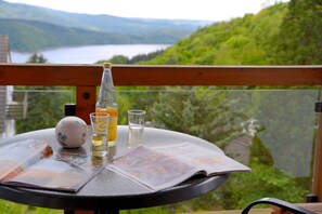 Une table ronde avec un journal, un verre, une bouteille et un objet décoratif.