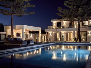 Une maison moderne à deux étages, dotée d’une piscine, d’un espace extérieur aménagé et de grandes fenêtres bien éclairées.