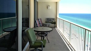 Un balcon avec une table et des chaises, une vue sur l’océan et une balustrade.
