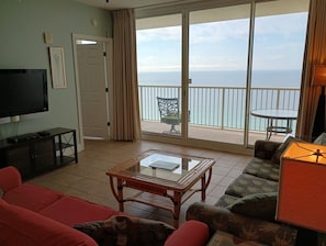Relax in this stylish living room with a large flat-screen TV, comfortable seating area, and sliding glass door to a balcony with ocean views.