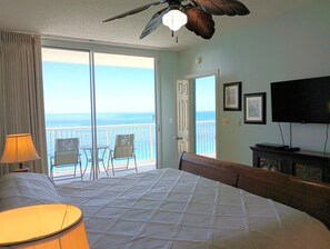 Relax in this serene room with a large bed, ceiling fan, and ocean views from the balcony.