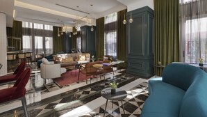 En modern hotellobby med ett rutmönstrat golv, en sittgrupp med soffor och fåtöljer samt en bardisk.