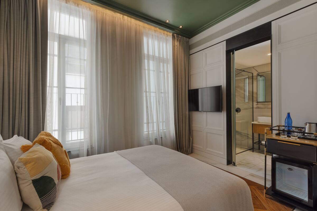 A hotel room with a large bed, a TV, and a minibar.