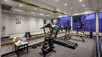 Un gimnasio moderno con equipamiento cardiovascular, máquinas de pesas y un espejo grande.