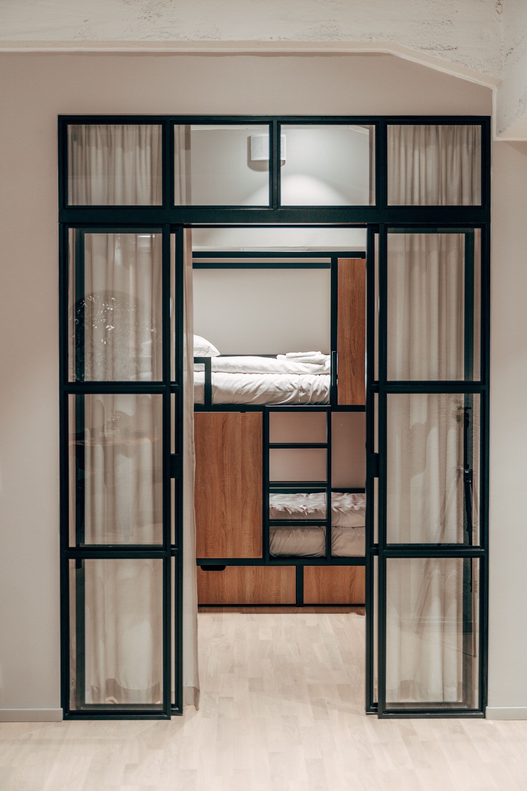 A room with a bunk bed, a wooden cabinet, and a glass partition.