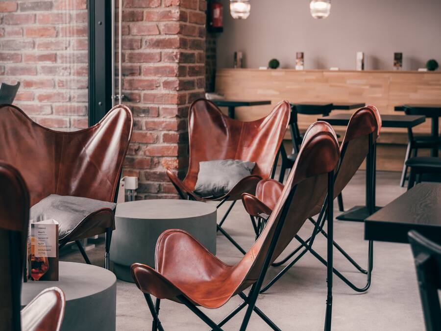 Un área de descanso moderna con sillones de cuero, una mesa redonda y farolillos de papel colgantes.