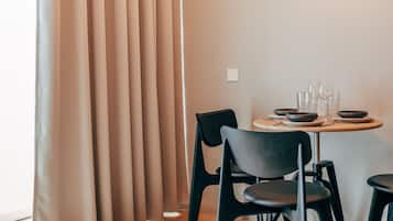 A modern dining area with a round table, black chairs, and a light fixture on the wall.