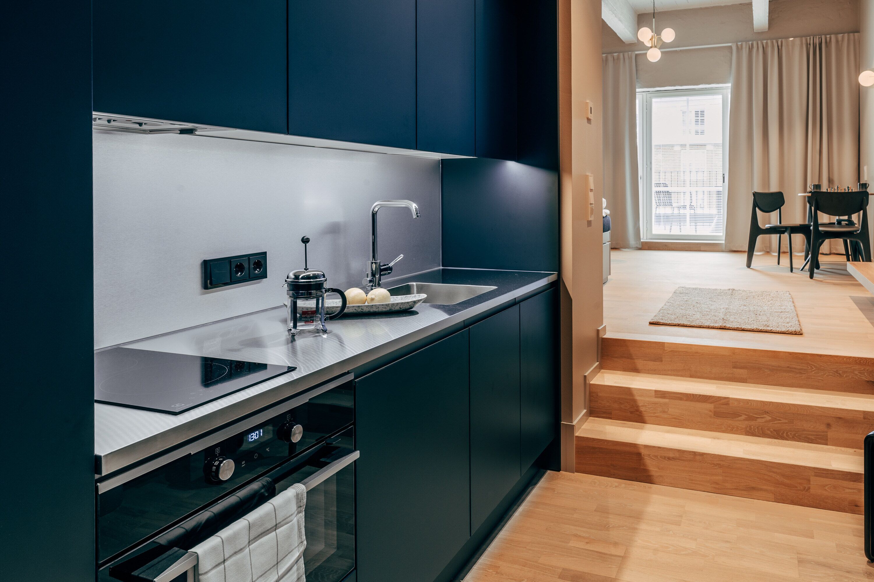 A modern kitchen with dark cabinets, a stainless steel sink, and a built-in oven.
