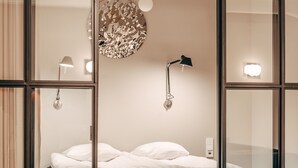 A bedroom with a bed, bedside lamps, a round mirror, and a blue sofa. - Unity Tampere - A Studio Hotel (Tampere)