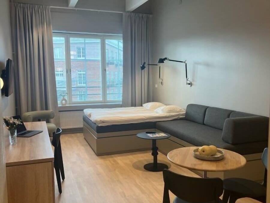 Una habitación moderna y funcional con cama, sofá y zona de comedor.