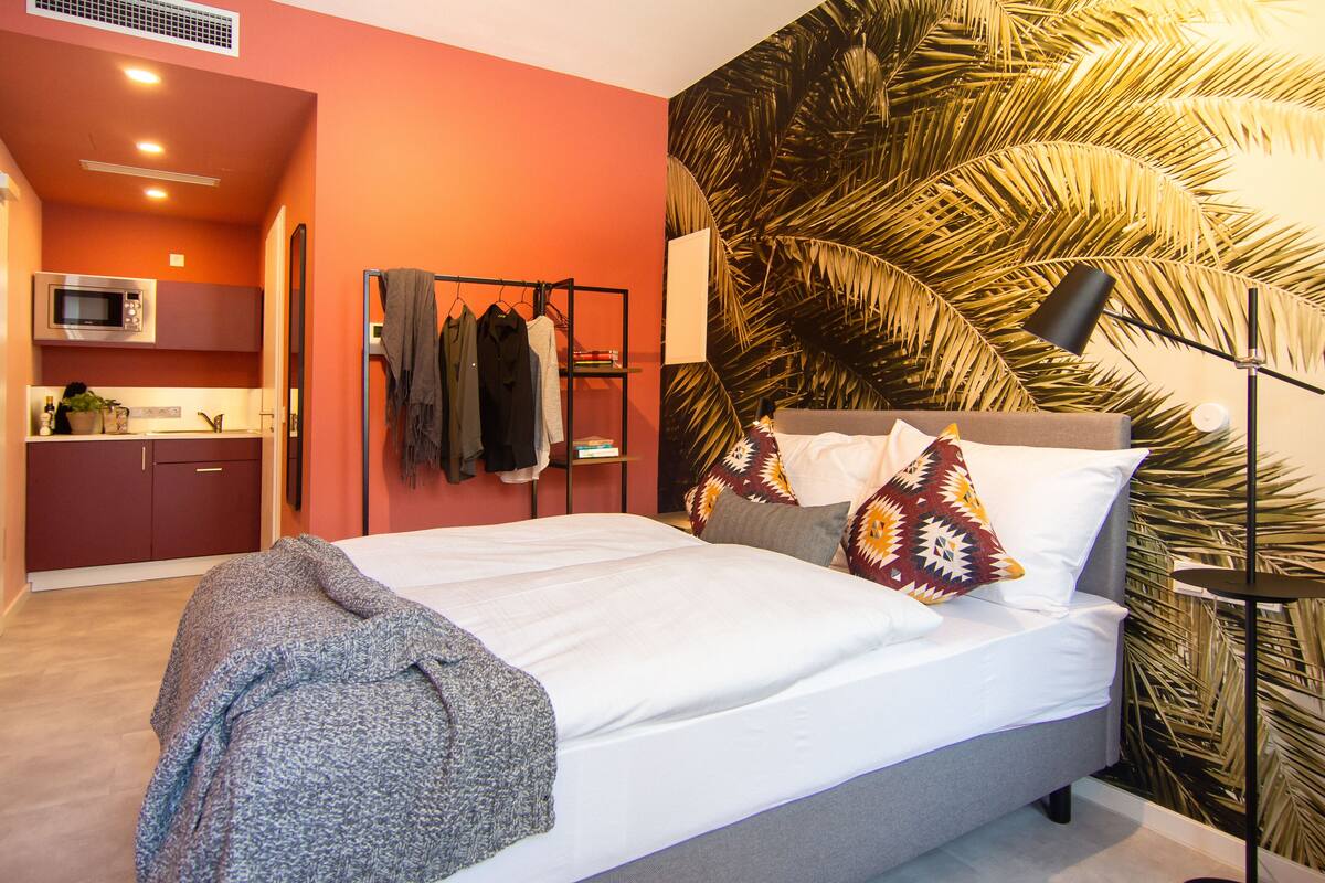 Une chambre comprenant un lit, une armoire, un portant à vêtements et un coin cuisine équipé d’un four à micro-ondes.