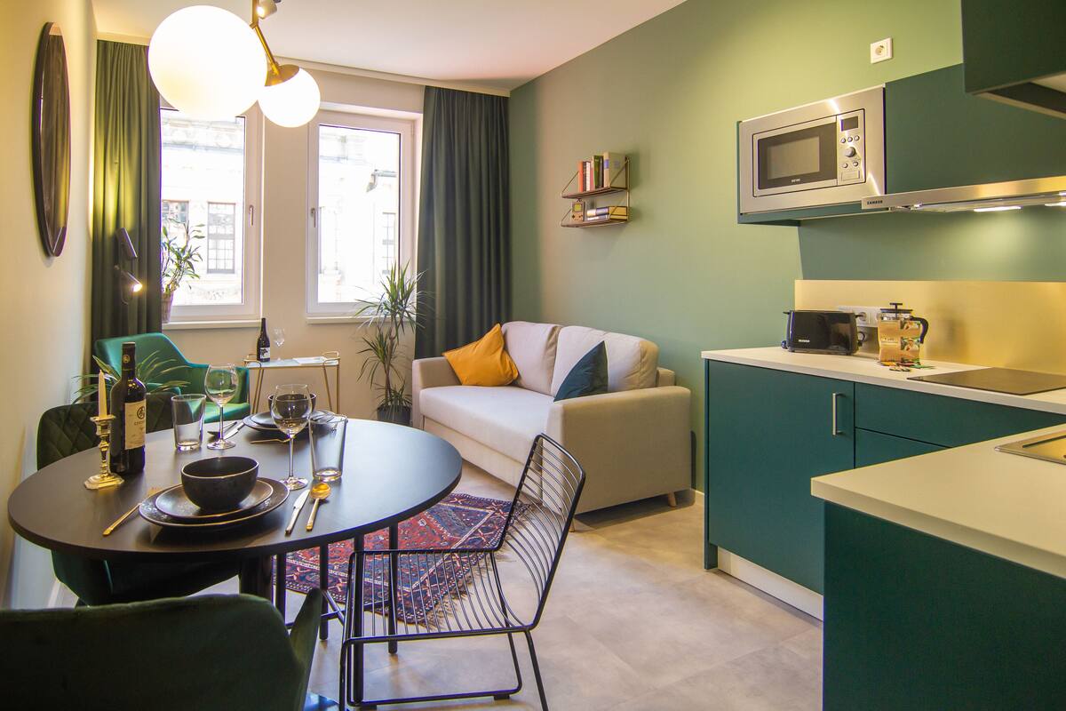 Un salon moderne comprenant un canapé, une table à manger et un coin cuisine équipé d’un four à micro-ondes.