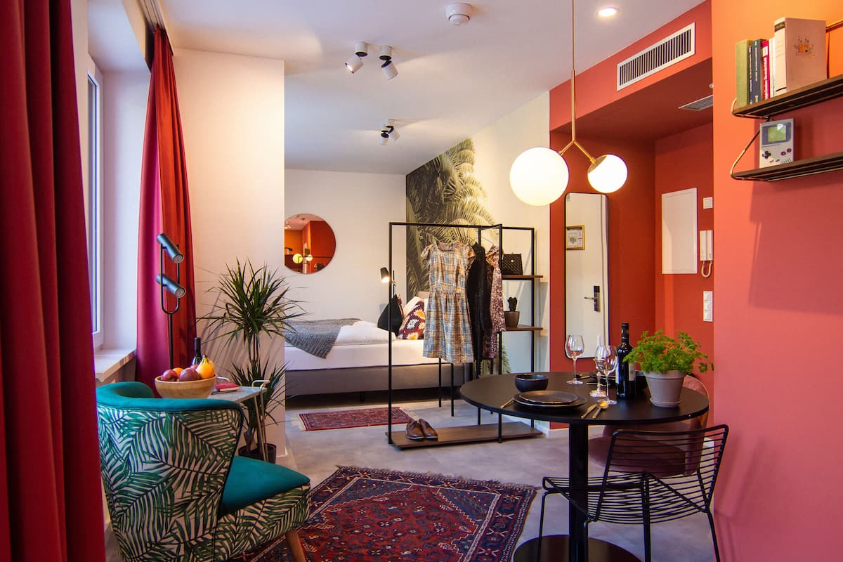 Une chambre d’hôtel moderne comprenant un lit, un coin repas, un miroir et un mur d’accent de couleur rouge.