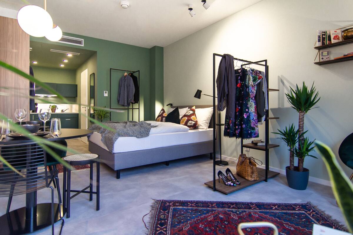 Une chambre à coucher moderne avec un lit, une table de chevet et un portant à vêtements.