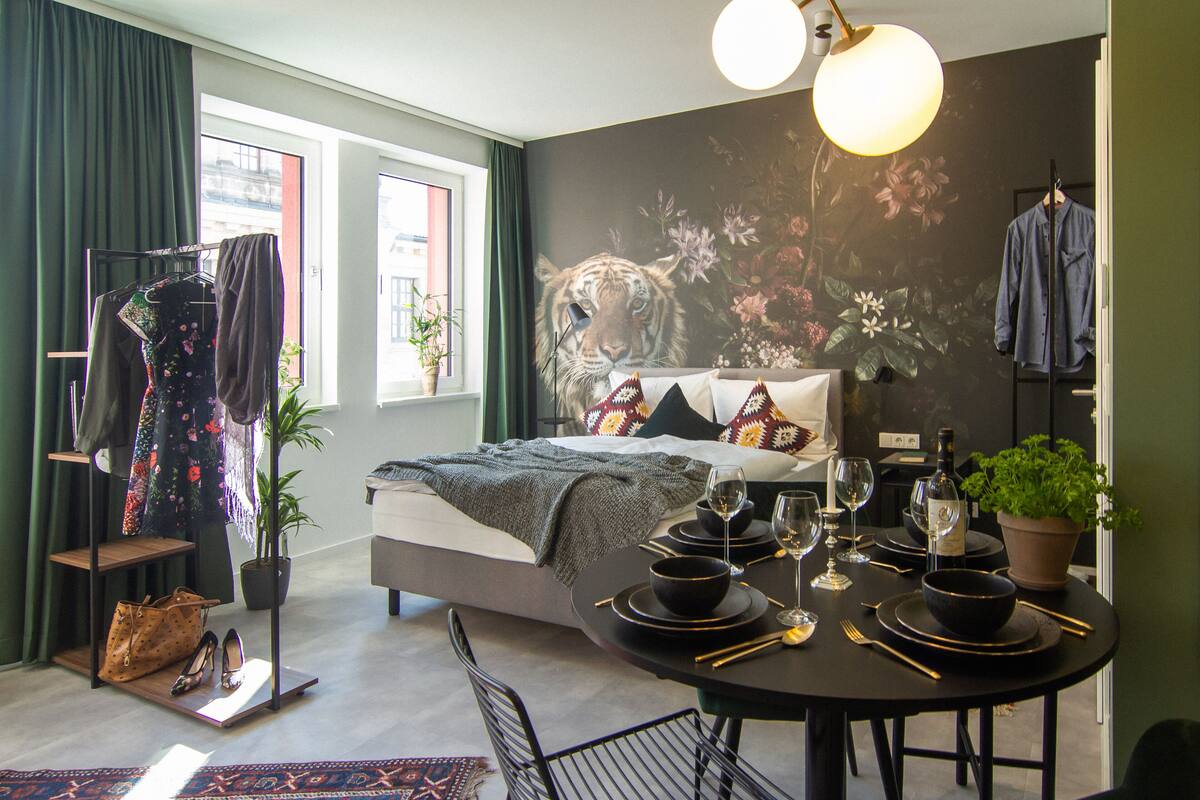 Une chambre à coucher moderne avec un lit, une table à manger dressée avec de la vaisselle, et une fresque murale.