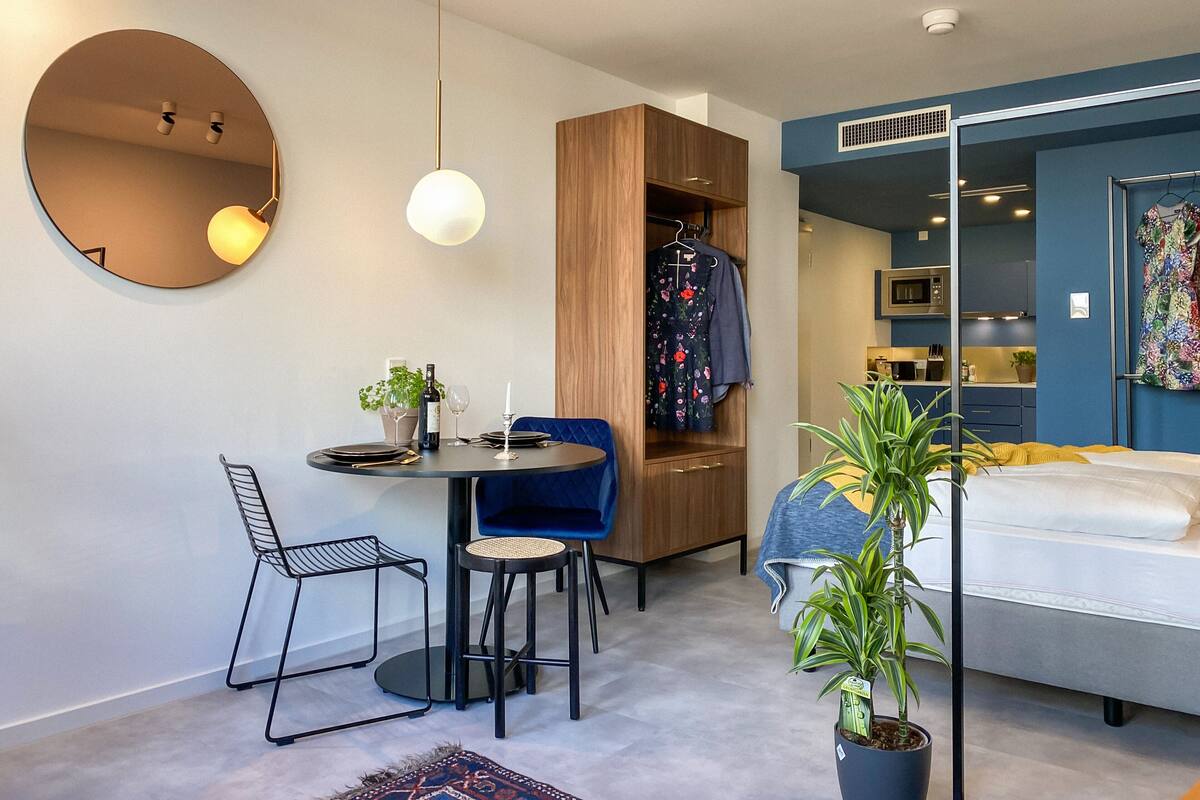 Une pièce compacte comprenant un coin repas, un lit, une armoire et une petite kitchenette.