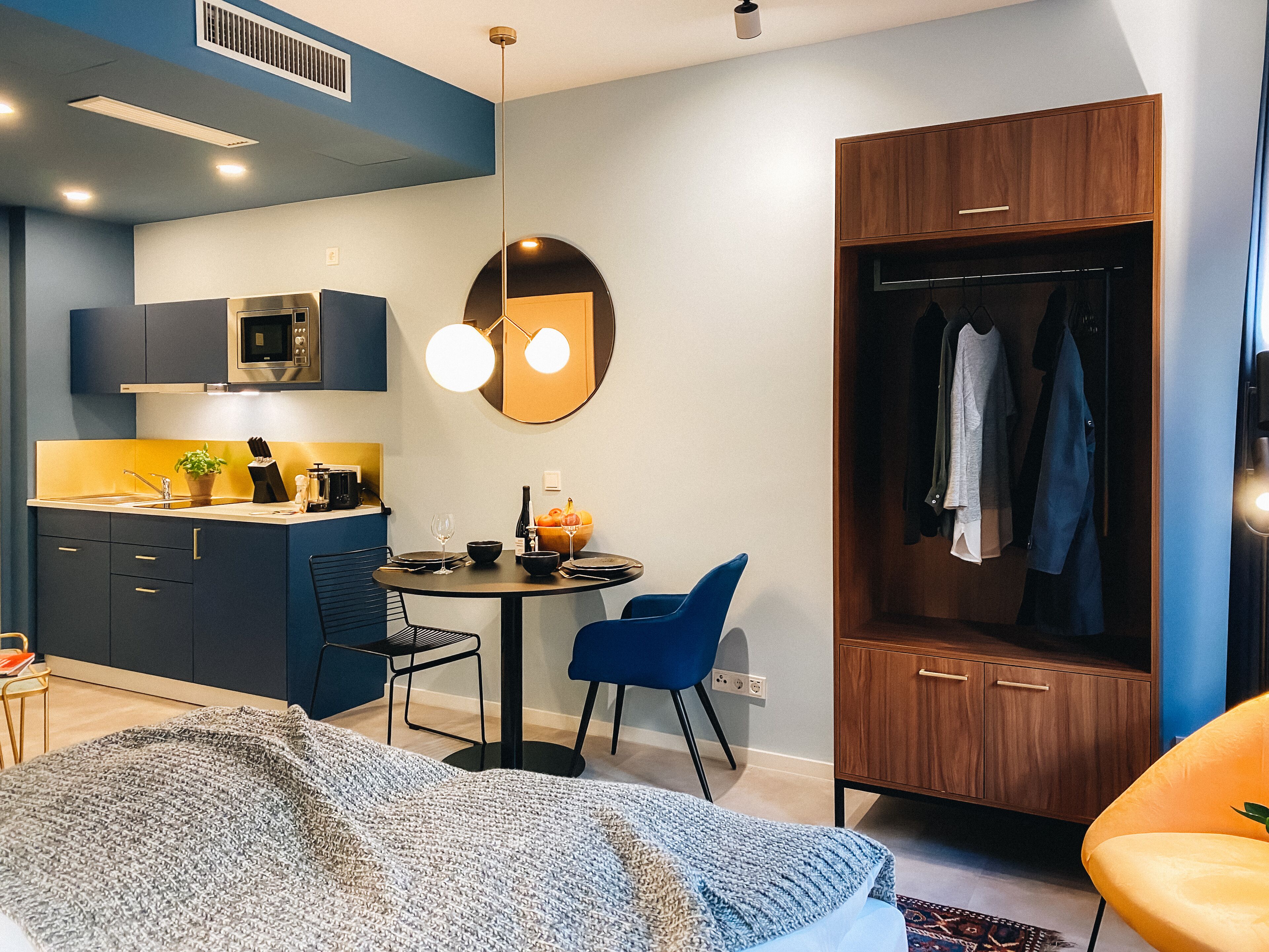 Una habitación compacta y moderna con kitchenette, comedor y vestidor.