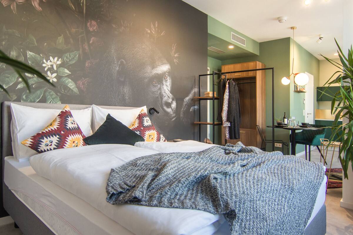 Une chambre moderne avec un grand lit, une armoire, un bureau et un mur vert.