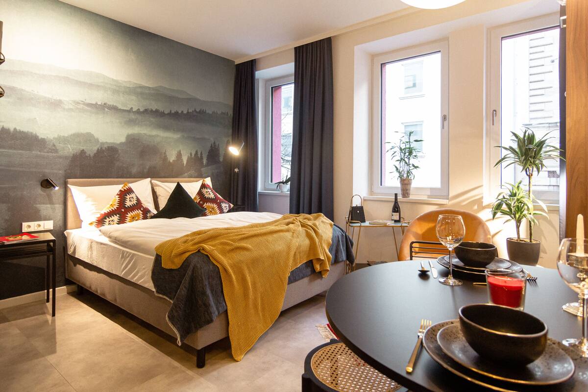 Une chambre d’hôtel moderne dotée d’un grand lit, d’une table à manger et offrant une vue sur la ville par les fenêtres.